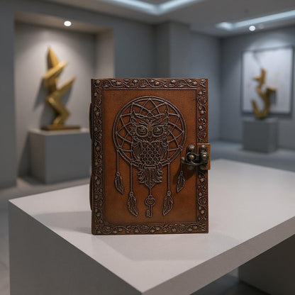Decorative brown leather notebook with owl and dreamcatcher design on a white platform.
