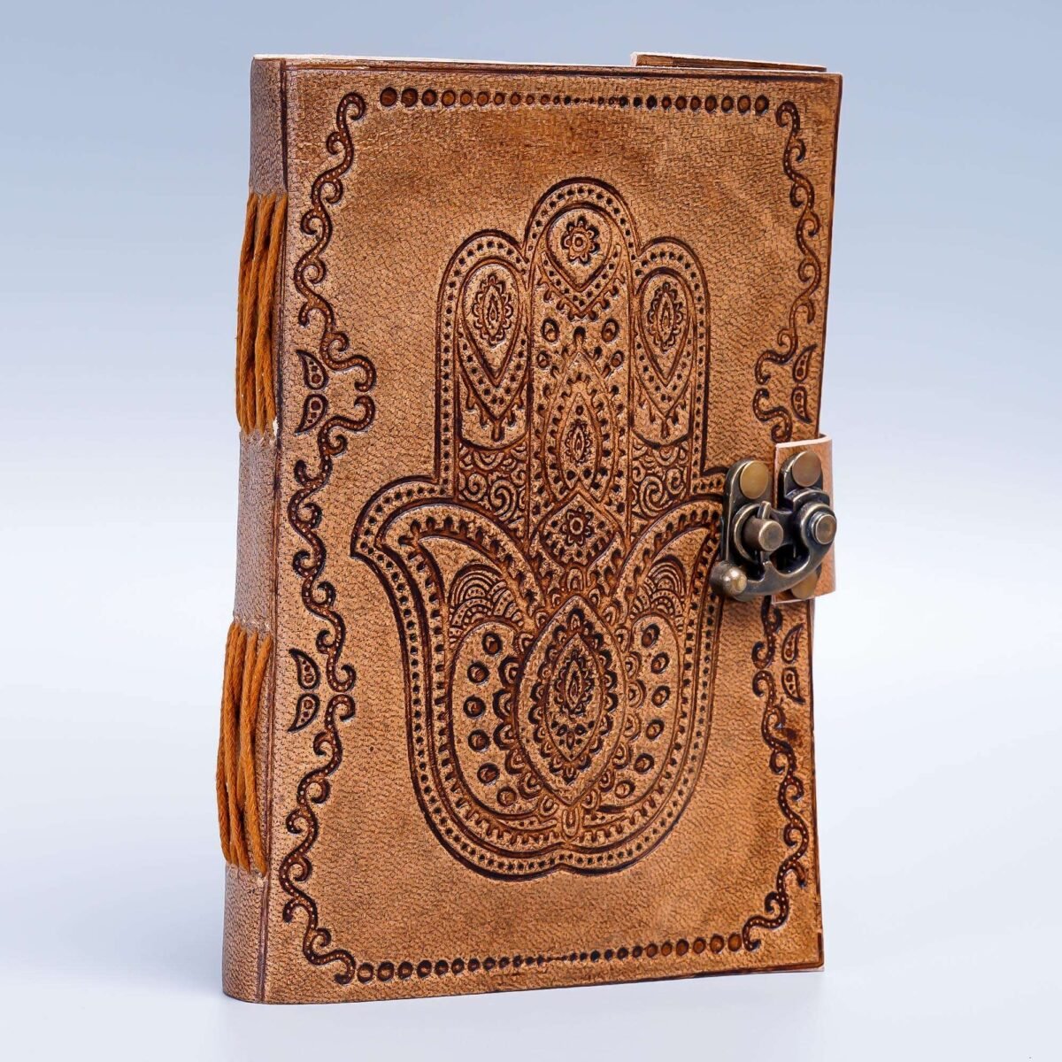 Brown leather journal with intricate designs and a lock on a light blue background