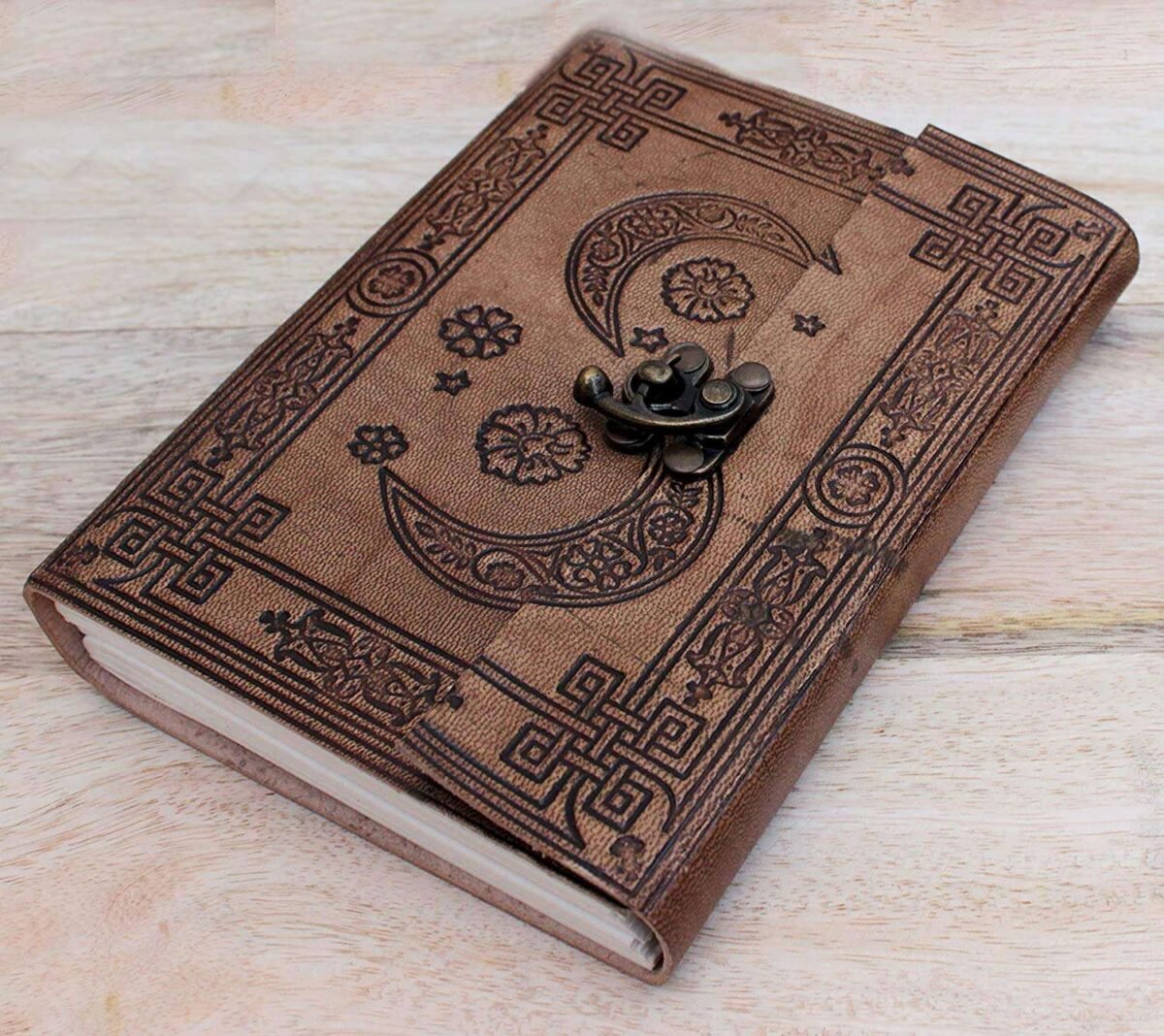 Brown leather notebook with embossed designs on a wooden surface