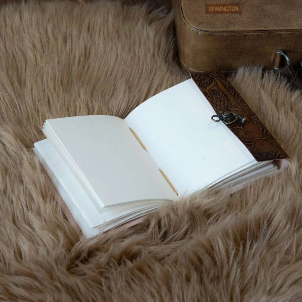 Open book on a fluffy brown rug next to a leather suitcase