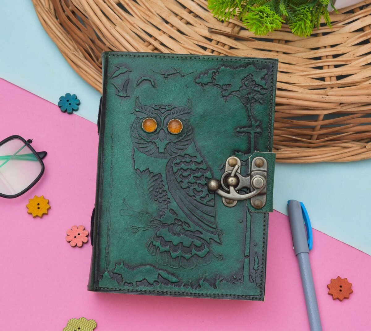 Green leather notebook with owl design on a colorful background