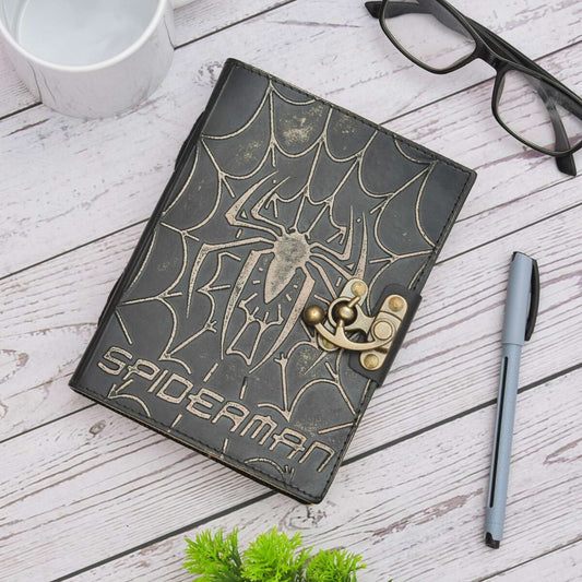 Spider-Man themed notebook with lock on a wooden surface with a cup, glasses, and pen.