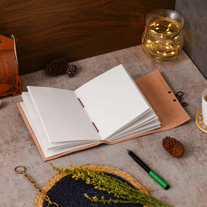Open notebook on a textured surface with a pen, small plant, and decorative items.