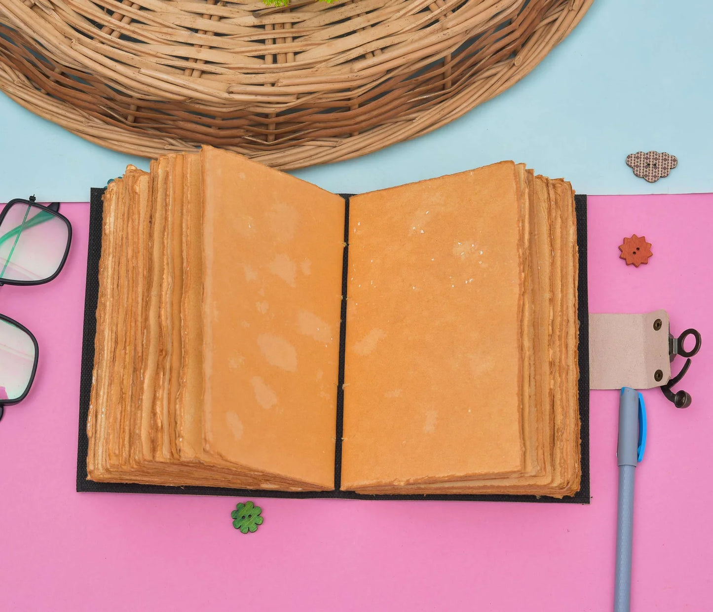 Open book with textured pages on a pink surface with decorative items.